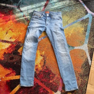  slim jeans från Jack & Jones - Säljer ett par ljusblå slim fit jeans från Jack & Jones, modell Glenn. Klassisk femficksdesign, knappgylf och smal passform. Perfekta för dig som gillar en stilren och enkel look. Storlek W28 L30.