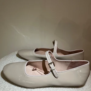 Beige ballerinaskor med spänne - Säljer ett par stilrena beige ballerinaskor från Zara med rund tå och justerbart spänne över foten. Så fina! Aldrig använda.