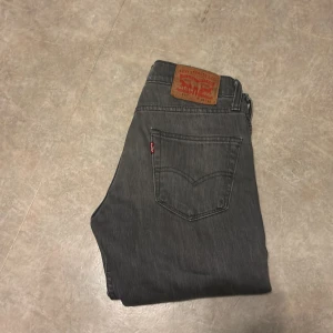 Grå Levi's 511 jeans W28 L30 - Säljer ett par grå Levi's 511 jeans med klassisk femficksdesign och rakt snitt. Jeansen har en snygg tvättad look, läderpatch bak i midjan och röd Levi's-tagg på bakfickan. Perfekta för dig som gillar en smalare passform.