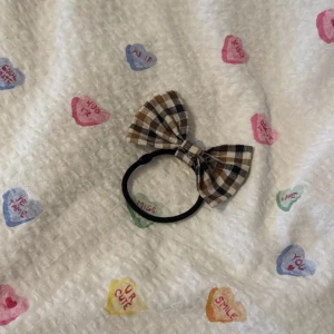 Rutigt hårsnodd med rosett - Söt hårsnodd med en brun, svart och vit rutigt rosett. Säljer pga kommer inte till användning 