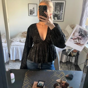 Svart glittrig blus från Gina Tricot - Supersnygg svart glittrig blus med v-ringning och långa ärmar. Jätte snygg till fest mm💕 använd en gång! (Inga defekter) 
