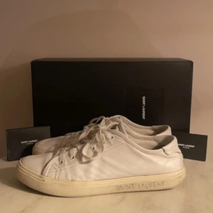 Vita sneakers från Saint Laurent - Säljer ett par klassiska vita sneakers från Saint Laurent med diskret logga på sidan av sulan. Köpte dessa av en kompis men fick ett par nya skor i present därav säljer jag dessa.