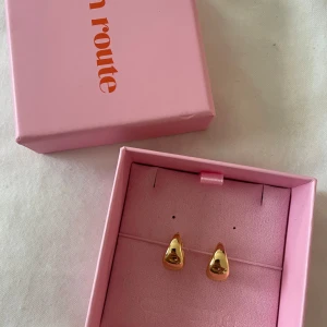 Guld pläterade örhängen från En Route - Aldrig använda! Säljer ett par stilrena, chunky örhängen i guld plöterad metall från En Route. De har en mjukt droppformad design och kommer i original ask. Perfekta för att lyfta vilken outfit som helst!