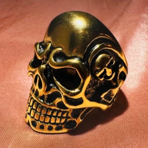 Guldfärgad dödskallering - Tung och uttrycksfull dödskallering i guldpläterat rostfritt stål. Detaljerat snidad med blank finish – perfekt för alternativ, biker eller gothstil. Höjd ca 3,3 cm, storlek ca 20,6 mm (US 10). Ny och oanvänd. En accessoar som syns! Ingen prutning – bundlerabatt vid flera köp. Jag rensar smyckesskrin och garderob, kolla gärna mina andra annonser också!