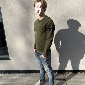 Olivgrön tröja från Stone Island - Säljer en olivgrön tröja från Stone Island med rund hals och långa ärmar. Tröjan har en diskret logotyp på ärmen och är perfekt för en avslappnad stil. Passar bra till jeans och sneakers. Inköpt på Nk! 