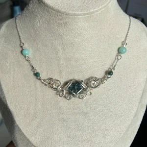 Handgjort halsband med silvertråd och blågrön sten🦋 - Unikt halsband med intrikat virad silvertråd och blågrön sten i mitten. Kedjan har små blågröna pärlor på sidorna och justerbart lås. Perfekt för dig som gillar bohemisk och elegant stil.