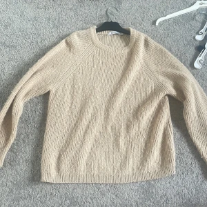 Beige stickad tröja från NA-KD - Säljer en beige stickad tröja från NA-KD i storlek S. Tröjan har rund halsringning och långa ärmar. Perfekt för lager-på-lager och enkel att matcha med olika outfits.