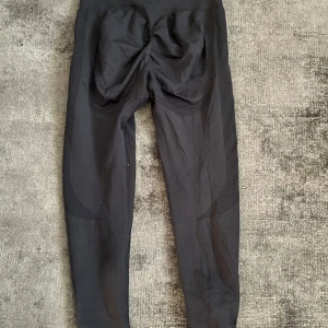 Svarta leggings med scrunch-detalj - Svarta leggings med scrunch-detalj bak som framhäver formen. Hög midja och stretchigt material som sitter tight mot kroppen. Perfekta för gymmet eller vardagslooken.