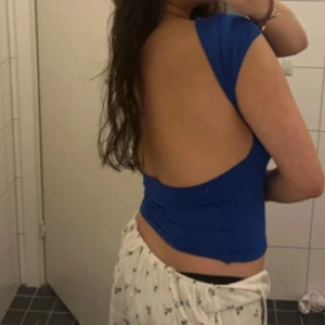 Blå topp med öppen rygg - Säljer en blå topp med korta ärmar och helt öppen rygg. Toppens material känns stretchigt och följsamt, perfekt för en trendig look. Snygg att styla till både jeans och kjol. Passar XS och S