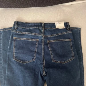 Mörkblåa Jeans - Helt nya, oanvända mörkblå skinny jeans i modellen Jane med klassisk femficksdesign och kontrastsömmar. Byxorna har medelhög midja och smal passform hela vägen ner. Perfekta för dig som gillar en tight siluett och enkel stil.