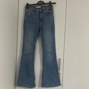 Blå bootcut jeans från Pull&Bear - Säljer ett par klassiska blå jeans från Pull&Bear med bootcut-passform. Jeansen har fem fickor, normalhög midja och är tillverkade i denim. Perfekta för dig som gillar en tidlös stil med lite utsvängda ben.
