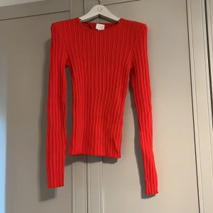 Röd ribbad långärmad topp - Säljer en snygg röd ribbad topp med lång ärm och rund halsringning. Tröjan har en tight passform och är perfekt att styla till både jeans och kjol. Enkel men trendig design. 