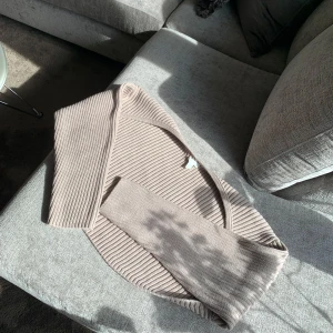 Beige ribbad kofta - Säljer en beige ribbad bolero med lång ärm. Toppen har en snygg design och är tillverkad i ett mjukt stickat material som känns skönt mot huden. Det är den perfekta koftan för att styla med yoga stilen eller för mysig hemma look. 
