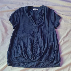 Mörkblå blus från Hampton Republic - Säljer en mörkblå blus från Hampton Republic i storlek M. Blusen har korta ärmar, v-ringning och är tillverkad i ett lätt och mjukt tyg. Perfekt för vår och sommar, enkel att matcha till olika outfits.