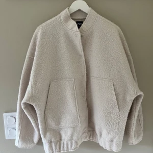 Offwhite bomberjacka från ZARA stl xs - Oversize bomberjacka från Zara med fickor fram. Jackan har en rund halsringning och resår nedtill. Stängs med tryckknappar.   Storlek XS men passar nog de flesta beroende på hur oversize du vill ha den. .