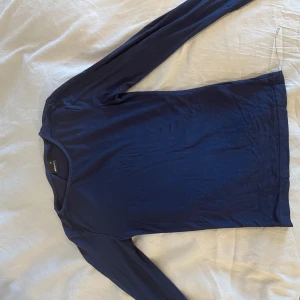 Mörkblå långärmad topp från Uniqlo - En enkel och stilren mörkblå långärmad topp från Gina med en liten slits i armarna 