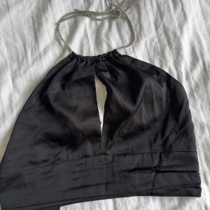 Svart topp med glitter band - En väldigt fin svart topp med glitter band + urringning från Nelly. Använd endast en gång. I storlek 36 s.