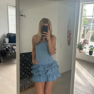 Ljusblå jeansklänning - Supersöt axelbandslös kort jeansklänning i ljusblå denim med volangdetaljer och dragkedja i ryggen. Använd 1-2 ggr endast🫶🏻