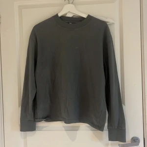 Grå sweatshirt från Zara - Säljer en enkel och stilren grå sweatshirt från Zara. Tröjan har rund halsringning, långa ärmar och ribbade muddar vid hals, ärmslut och nederkant. Perfekt basplagg till garderoben!