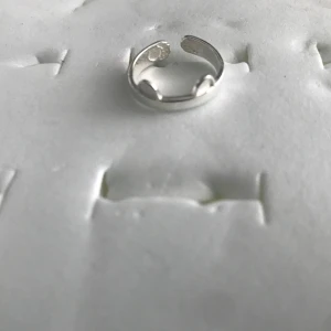 925 Silverpläterade ring med kattöron - En justerbar ring i silverfärg med små kattöron på ovansidan. Perfekt accessoar för dig som gillar djur eller vill ha något lekfullt och unikt i din smyckessamling. Stämplade, helt ny 