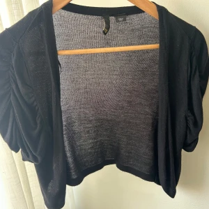 Svart bolerotopp med korta ärmar - Säljer en svart bolerotopp med korta, puffiga ärmar och öppen front. Från H&M! Skriv för fler bilder❣️