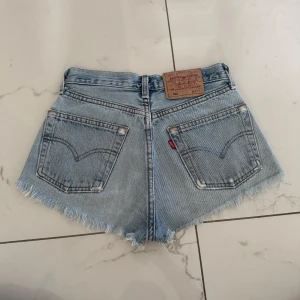 Levi's jeansshorts - Ljusblå jeansshorts från Levi's med klassisk femficksdesign, vintage 501. Perfekta för sommaren. Det står storlek 26 på de men de ör vintage och skulle säga att de är storlek 24 idag.