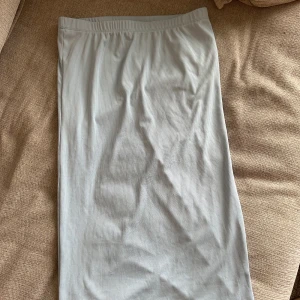 Ljusblå ribbad långkjol från Vero Moda - Säljer en ljusblå långkjol från Vero Moda. Kjolen är ribbad och har en elastisk midja för bekväm passform. Perfekt för dig som gillar en enkel och stilren look. Endast en liten defekt framtill som syns på närbilden