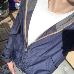Blå Windbreaker från Lee - En blå Windbreaker från Lee i mycket bra skick. Perfekt till vindiga vårdagar eller sena sommarkvällar!