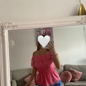 Rosa offshoulder spettröja  - Säljer en söt rosa topp med offshoulder-modell och vackra spetsdetaljer. Toppen har resår i midjan för en smickrande passform och är perfekt för somriga tillfällen. Materialet är lätt och luftigt med fina spetsmönster.