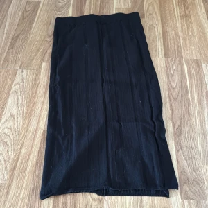 Svart långkjol från lager 157  - En stilren svart långkjol med rak passform. Kjolen har en diskret struktur i tyget och är enkel att matcha med olika toppar. Perfekt för dig som gillar minimalistisk stil.