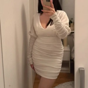 Vit klänning från NA-KD - Bara använd en gång. Ärmarna är justerbara och det finns ett band man knyter i midjan om man vill. Den är använd 1 gång. 