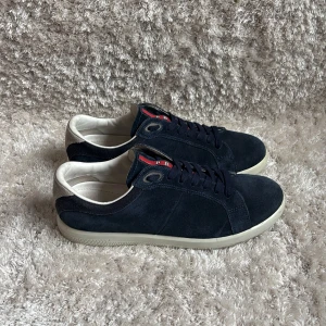 Prada skor - Snygga mörkblå sneakers från Prada i mocka med vita detaljer och vit sula | Väldigt eftertraktade och perfekt par unika skor för sommaren | Nypris ligger på 6600kr | Storlek är 7,5US så passar 41,5