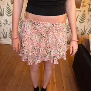 Rosa mönstrad volangkjol från Zara - Supersöt kort kjol från Zara i rosa och vitt med paisleymönster och volangdetaljer. perfekt för en trendig och feminin look. Storlek M men liten i storleken passar Xs/S 