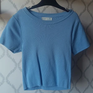 Ljusblå stickad topp från Primark - Säljer en ljusblå stickad topp från Primark med korta ärmar och rund halsringning. Toppen har en enkel och stilren design med ribbad kant vid halsen. Perfekt för en avslappnad och trendig look. Går att använda perfekt till vardags men kan ocksp gå att klä upp!! 65 kronor då den knappt är använd men priset kan diskuteras!! 