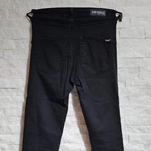 Svarta jeansbyxor från Now and Then - Säljer ett par svarta jeansbyxor från Now and Then i storlek XS. Byxorna har klassisk femficksdesign, silverfärgade knappar och raka ben. Perfekta för dig som gillar en enkel och stilren look.