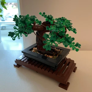 LEGO Bonsaiträd - Säljer ett LEGO bonsaiträd med gröna blad och brun stam. Trädet står i en svart rektangulär kruka på ett brunt ställ. Perfekt som dekorativ byggsats för dig som gillar växter och LEGO.