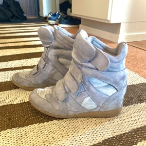 "Isabel Marant skor” - Säljer ett par gråa kilklackar med 4 kardborreband i bra skick. Skorna är gjorda i mocka liknande material. Perfekta för dig som vill ha lite extra höjd men ändå en bekväm sko🤩