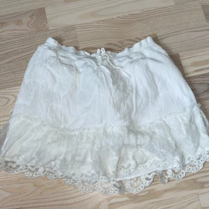 Vit kjol - Supersöt vit kjol med bred volangkant och fina spetsdetaljer. I midjan finns en knytgrej. Det är en jättefin sommarkjol från zara. Pris kan diskuteras!