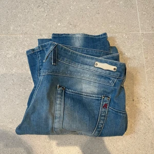 Blå skinny jeans från Replay - Säljer ett par blå skinny jeans från Replay med klassisk femficksdesign och snygga slitningar. Jeansen har normal passform i midjan och smalare ben. Perfekta för dig som gillar en stilren och modern look.
