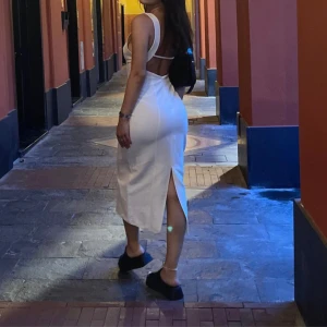 Vit långklänning med öppen rygg och slits från Zara - Säljer en elegant vit långklänning med breda axelband, öppen rygg och slits baktill. Klänningen har en figurnära passform och är tillverkad i ett lätt material som passar perfekt till sommarens tillfällen. Använd bara en gång, för bilder. 