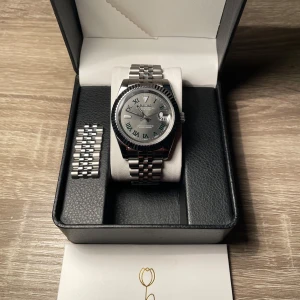 SEIKO klocka - Säljer en stilren SEIKO Datejust herrklocka i silver med grön urtavla och romerska siffror. Klockan har en klassisk länk i rostfritt. Levereras i originalask med extra länkdelar. Kan även juster storlek om det önskas😊