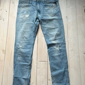 Replay ljusblå jeansbyxor herr - Säljer ett par ljusblå jeans från Replay, modell Anbass. Byxorna har klassisk femficksdesign, normal passform och slitna detaljer framtill. Midjemått W34 och längd L32. Perfekta för dig som gillar en avslappnad men snygg stil.