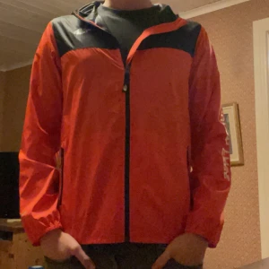  Windbreak jacka the north face  - Säljer en orange och svart vindjacka från The North Face med dragkedja framtill och huva. Jackan har långa ärmar och logga på bröstet. Perfekt för utomhusaktiviteter och enkel att packa med sig☀️ Jackan är som ny och endast använts ett fåtal gånger! Hör gärna av er vid fler bilder eller frågor🌟