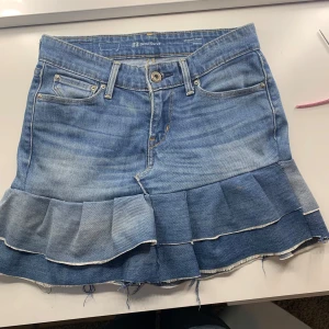 Jeanskjol med volang från Levi's - Säljer min älskade jeanskjol, som jag har gjort själv. Jeansen kommer ursprungligen från Levi’s men jag har sytt om dem till en kjol. Perfekt för dig som gillar denim och vill ha en kjol med lite extra detalj. Storleken är en barn storlek men passar xxs och xs. Kjolen är själv gjord så den kan ha något litet hål vid kanten och kjolen har även lite tecken på användning, men det tro jag skulle gå och tvätta bort fort. Pris går nog att dudkutera💕