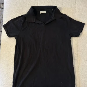 Svart piké t-shirt från Lindbergh - Svart piké t-shirt från Lindbergh i storlek M. Klassisk krage och korta ärmar, tillverkad i mjuk bomull. Stilren och enkel design utan mönster, perfekt för dig som gillar en clean look.