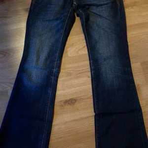 Tommy Hilfiger Sonora Bootcut Jeans - Mörkblå bootcut jeans från Tommy Hilfiger Denim, modell Sonora. Klassisk femficksdesign med snygga kontrastsömmar och Hilfiger-detaljer på bakfickan. Två knappar, Low waist. Skriv för fler bilder🙂