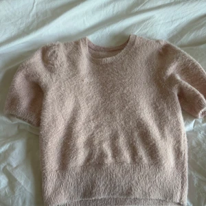 Ljusrosa fluffig stickad tröja - Supermjuk och fluffig ljusrosa stickad tröja med korta ärmar och rund hals. Perfekt för hösten. Vet ej storlek eller märke men passar XXS-S