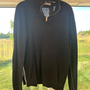 half zip - Svart långärmad tröja från Jack & Jones med half zip-dragkedja vid halsen. Tröjan har ribbade muddar och är i en klassisk, enkel modell som passar till mycket. Materialet känns mjukt och lätt, perfekt för lager-på-lager under höst och vinter. Ps finns 2 st inne på lagret