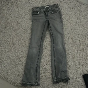 Grå bootcut jeans från ginatricot - Grå lågmidjade jeans från Gina, en 36a men passar 34 lika bra, väldigt stretchiga, har sprett upp benen men det går att sy tillbaka, annars en fin detalj, nypris 499