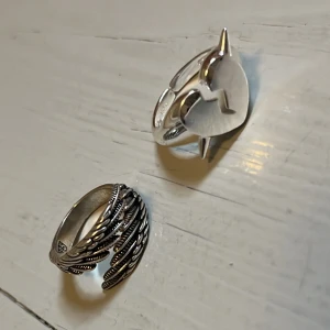 cool silverringar från lyla!:) - Säljer två snygga silverringar OBS HJÄRTRINGEN FINNS INTE KVAR!. Den ena har ett detaljerat fjädermönster som slingrar sig runt fingret,från lyla och är knappt använd och köpt för ca 250kr, är justerbar!